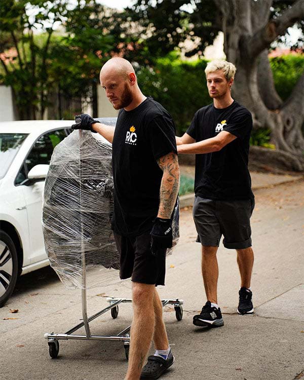 Two movers loading a wrapped large item